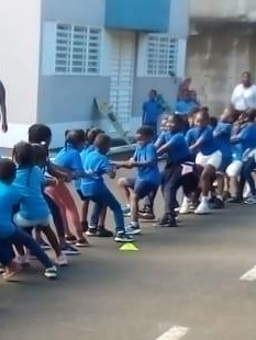 Deux groupes d'enfant tenant chaque côté d'une corde l'un derrière l'autre en pleine partie de tire à la corde